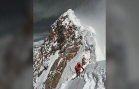 Everest keynote speaker climbing a fixed rope along the exposed summit ridge of Mount Everest