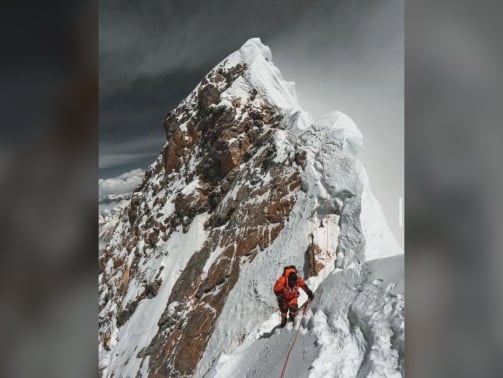 Everest keynote speaker climbing a fixed rope along the exposed summit ridge of Mount Everest